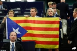 Belgium members of the European Parliament, Anneleen Van Bossuyt, left, Mark Demesmaeker and Helga Stevens, right, display a Catalan flag in support of the disputed independence vote Sunday in Catalonia during a session at the European Parliament.