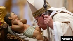 El papa Francisco besa la imagen del niño Jesús en la Basílica de San Pedro, en el día de la Epifanía.