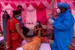 Seorang perempuan dikelilingi kerabatnya, menerima bantuan oksigen gratis di Gurudwara (kuil Sikh), di tengah pandemi COVID-19, di Ghaziabad, India, 6 Mei 2021. (REUTERS/Danish Siddiqu)