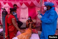 Seorang perempuan yang dikelilingi kerabatnya menerima bantuan oksigen secara gratis di Gurudwara (kuil Sikh), di tengah penyebaran penyakit virus corona (COVID-19), di Ghaziabad, India, 6 Mei 2021. (Foto: REUTERS/Danish Siddiqui)
