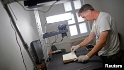 Photographer Jim Marshall, a member of the Foundation for the Preservation of Historical Heritage, photographs pages of a book in Bosnia's National Library in Sarajevo, Aug. 19, 2014. 