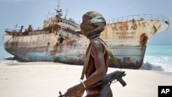 Abdi Ali, pirate somalien masqué, passe devant un bateau de pêche accosté après paiement d’une rançon à Hobyo, Somalie, 28 septembre 2012.