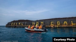 Aktivis Greenpeace menulis Coral not Coal di lambung tongkang batubara di Karimunjawa. (Foto: Greenpeace Indonesia)
