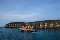 Aktivis Greenpeace menulis Coral not Coal di lambung tongkang batu bara di Karimunjawa. (Foto: Greenpeace Indonesia)