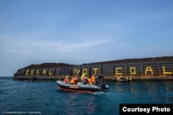 Aktivis Greenpeace menulis Coral not Coal di lambung tongkang batu bara di Karimunjawa. (Foto: Greenpeace Indonesia)
