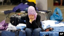A migrant woman covers her face as she sits on her bed at a first registration point for refugees in Neu Isenburg, Germany, Sept. 11, 2015. 