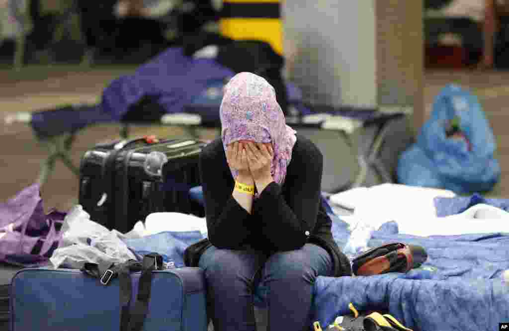 A migrant woman covers her face as she sits on her bed at a first registration point for refugees in Neu Isenburg, Germany.