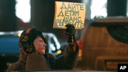 A woman opposing a bill that would ban adoptions of Russian children by Americans holds a sign reading 'Give the children a chance to live' during a picket at the entrance of the State Duma, in Moscow, Russia, December 21, 2012.