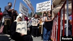 FILE - Women hold pictures of relatives who went missing during Lebanon's civil war, which took place from 1975 to 1990, during a protest in front of the government palace in Beirut, Sept. 18, 2014. 