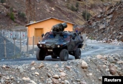 FILE - A Turkish military armoured personnel carrier drives past a small patrol base high in the mountains of Cukurca near the Iraqi border in southeastern Turkey.