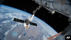 At the end of a previous resupply flight, a robotic arm reaches out to capture the SpaceX Dragon cargo spacecraft and prepare it to be pulled into its port on the International Space Station, April 17, 2015. 