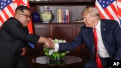 Le président des États-Unis, Donald Trump, serre la main du dirigeant nord-coréen Kim Jong Un lors de leurs premières rencontres au resort de Capella sur l'île de Sentosa, à Singapour, le 12 juin 2018.