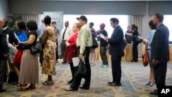 FILE - People are seen waiting in line to meet with recruiters during a job fair in Philadelphia, Pennsylvania.
