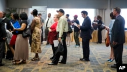 FILE - People are seen waiting in line to meet with recruiters during a job fair in Philadelphia, Pennsylvania.