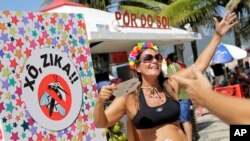 Una brasileña celebra el carnaval en la Playa de Ipanema, con un cartel que dice "Fuera Zika".
