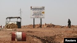 An Algerian soldier stands at a checkpoint near a road sign indicating 10 km (6 miles) to a gas installation in Tigantourine, the site where Islamist militants have been holding foreigners hostage according to the Algerian interior ministry, in Amena Janu
