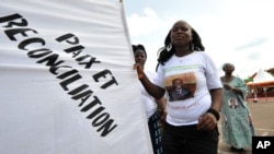 A supporter of Ivorian President Alassane Ouattara dances as she holds a banner reading in French "Peace and reconciliation" during a meeting on April 22, 2012 in Guiglo. 