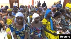 FILE - A still image taken from video shows a group of girls, released by Boko Haram jihadists after kidnapping them in 2014 in the north Nigerian town of Chibok, sitting in a hall as they are welcomed by officials in Abuja, Nigeria, May 7, 2017.