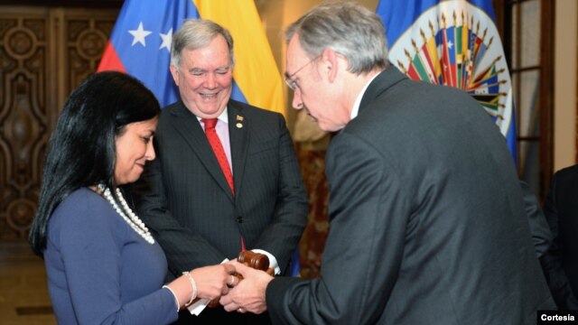La canciller venezolana recibe el mallet de manos del embajador uruguayo, Hugo Cayrús. Atrás, embajador Roy Chaderton.