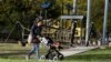 FILE - A woman and child pass a closed playground in Melbourne, Australia, August 17, 2021, as the city battles an outbreak of the Delta variant of coronavirus.