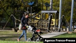 FILE - A woman and child pass a closed playground in Melbourne, Australia, August 17, 2021, as the city battles an outbreak of the Delta variant of coronavirus.