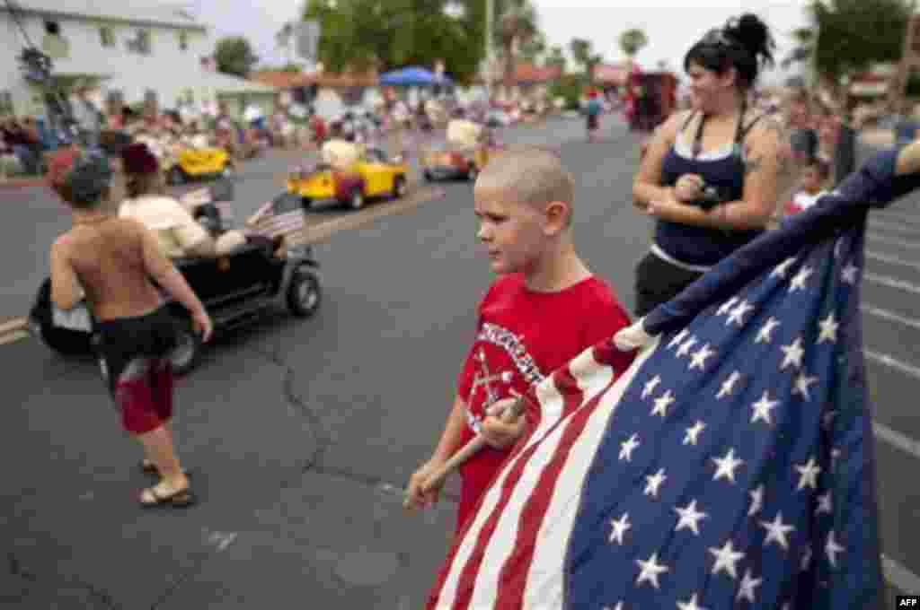 Ten-year-old Austin Kelley, right, watches as floats and other entrants roll along Nevada Way in the 63rd Annual Boulder City Damboree Parade, Monday, July 4, 2011, in Boulder City, Nev. (AP Photo/Julie Jacobson)