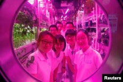 Volunteers smile from inside a simulated space cabin in which they temporarily live as a part of the...