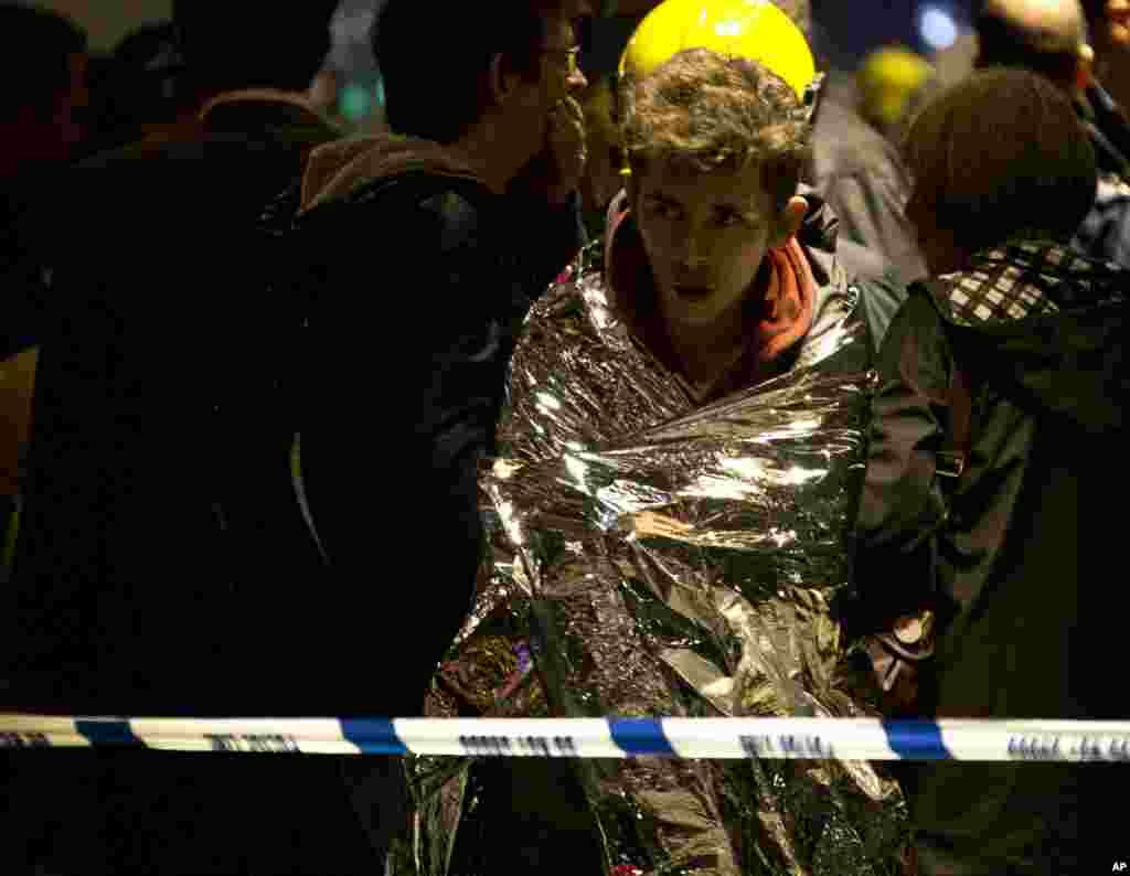 A man wraps himself in an emergency foil blanket provided by rescue services after part of the ceiling collapsed during a performance at the Apollo Theatre, Shaftesbury Avenue, London, Dec. 19, 2013.