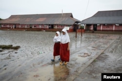 FILE - Students walk in the yard of the Pantai Bahagia Elementary School, before tide comes in, in Bekasi, West Java province, Indonesia, Feb. 1, 2018.