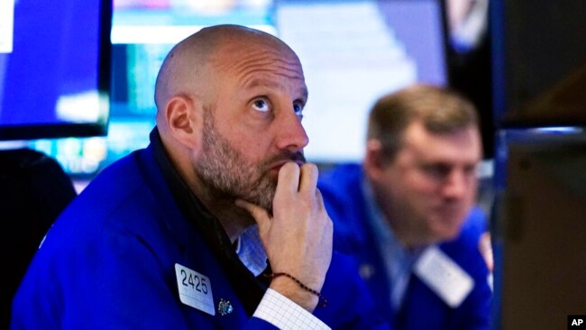 Specialist Meric Greenbaum, left, works at his post on the floor of the New York Stock Exchange, Nov. 26, 2021. Stocks closed sharply lower after a coronavirus variant from South Africa appeared to be spreading across the globe.