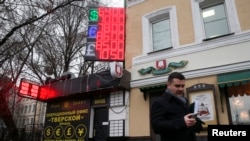 FILE - A man walks past a display with currency exchange rates in Moscow December 16, 2014.