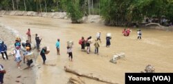 Para relawan kemanusiaan menyeberangi sungai yang mulai surut untuk mengantarkan logistik bantuan bahan makanan bagi warga terdampak banjir bandang di dusun 3, Desa Bangga, Dolo Selatan, Kabupaten Sigi, Sulawesi Tengah, 1 Mei 2019. (Foto: VOA/Yoanes)