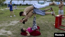 A woman (bottom) balances two men with her feet as students practice at an acrobatic school in Sanwang village, Anhui province, China, July 30, 2015. With a population of 1.37 billion, China has more men than women. The current ratio is at about 105:100.