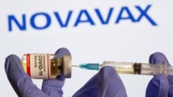 In this file photo, a woman holds a small bottle labeled with a "Coronavirus COVID-19 Vaccine" sticker and a medical syringe in front of adisplay of aNovavax logo in this illustration taken, October 30, 2020. (REUTERS/Dado Ruvic)