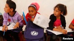 FILE - Syrian refugee children attend an English lesson inside a makeshift school tent during a visit by UNICEF Executive Director Anthony Lake.
