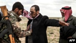 FILE - Men suspected of being Islamic State are searched by a member of the Kurdish-led Syrian Democratic Forces (SDF) after leaving the IS group's last holdout of Baghuz, in Syria's northern Deir Ezzor province, Feb. 27, 2019.