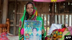 Mosammat Rashida tenant un portrait de son mari tué par un tigre du Bengale en 2009, Shyamna, Bangladesh, 11 novembre 2019.