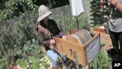 Katherine Jolda pedals to power two large spinning metal drums that brush out wool to be used for locally-made clothing and accessories.