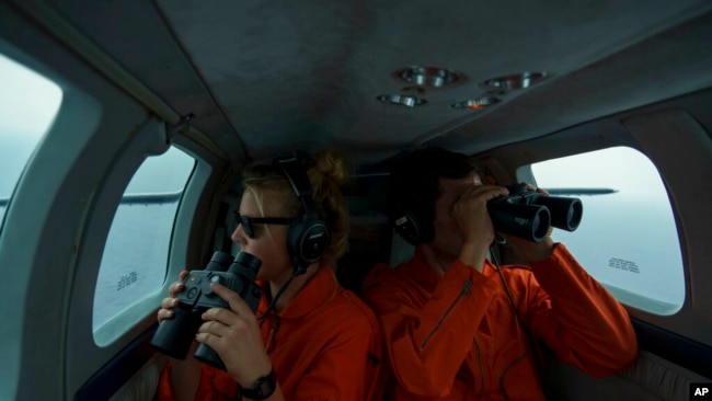 German volunteers Leona Blankenstein, left, and David Lohmueller search from aboard the Seabird for migrant boats in distress as they fly over the Mediterranean Sea between Libya and the Italian island of Lampedusa, Oct. 5, 2021.
