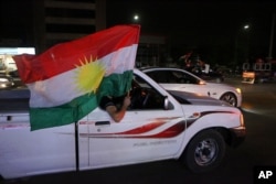 Iraqi Kurdish men celebrate as they wave Kurdish flags in the streets after the polls closed in the controversial Kurdish referendum on independence from Iraq, in Irbil, Iraq, Sept. 25, 2017.