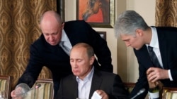 Businessman Yevgeny Prigozhin, left, serves food to Russian Prime Minister Vladimir Putin, center, during dinner at Prigozhin's restaurant outside Moscow, November 11, 2011. (Mikhail Japaridze/AP))