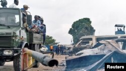 Security personnel sitting on a truck watch burned vehicles at the front gate of the Makala prison after it was attacked by supporters of jailed Christian sect leader Ne Muanda Nsemi in Kinshasa, Democratic Republic of the Congo, May 17, 2017. 