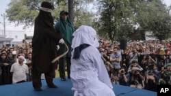 A Shariah law official whips a woman who is convicted of prostitution during a public caning outside a mosque in Banda Aceh, Indonesia, April 20, 2018. Indonesia's deeply conservative Aceh province on Friday caned several unmarried couples for showing affection in public and two women for prostitution.