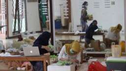 Para pedagang menyiapkan paket barang untuk dikirim ke pelanggan selama Pasar Minggu Pahingan di Jakarta, Minggu, 29 November 2020. (AP Photo / Achmad Ibrahim)