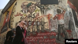 Egyptians walk past graffiti on a wall at Tahrir Square in Cairo, January 16, 2013.