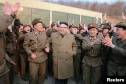김정은(가운데) 북한 국무위원장이 서해 위성발사장에서 신형 로켓엔진 지상 분출실험 현장을 참관한 뒤 관계자들과 함께 자축하고 있다. 조선중앙통신이 19일 공개한 사진.