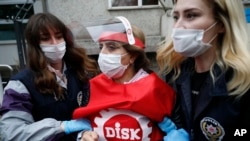 Polisi mengenakan masker untuk melindungi diri dari virus corona, menangkap seorang pengunjuk rasa dalam aksi protes Hari Buruh di Istanbul, Turki, 1 Mei 2020. 