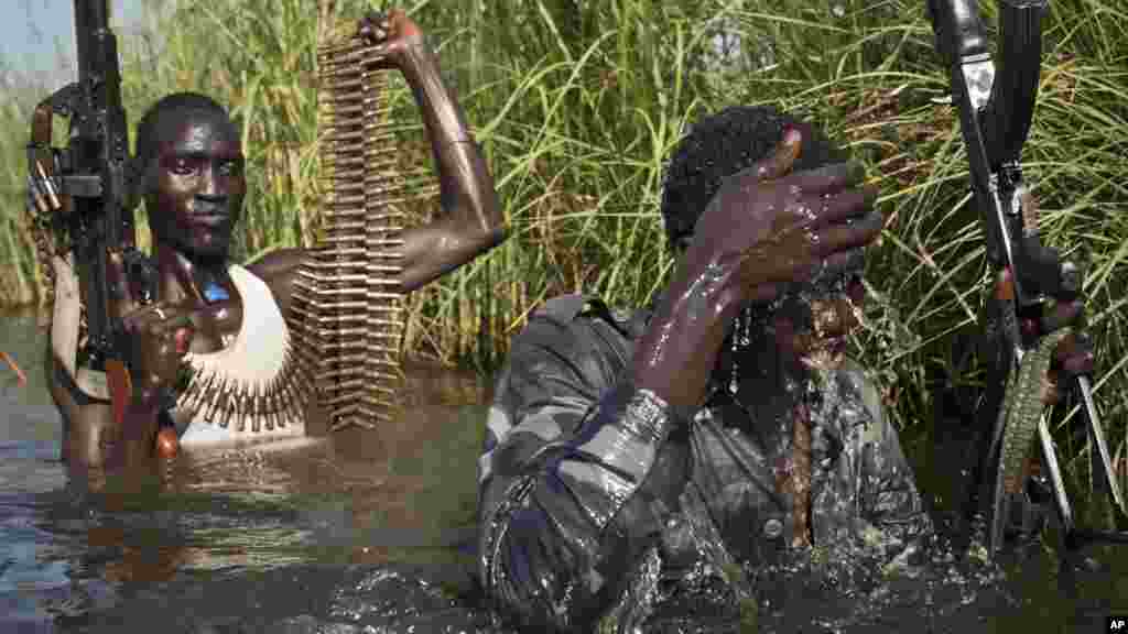 Des rebelles en patrouille encadrent des civiles de l&rsquo;ethnie Nuer qui traversent les eaux dans un camp près de la base de l&rsquo;ONU à Bentiu, 27 octobre 2015. . (AP Photo/Matthew Abbott)