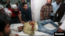 Hospital staff move a stretcher with an injured man after a train struck members of a crowd seated on tracks in Amritsar, India, Oct. 19, 2018.