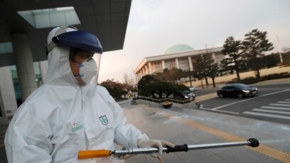 Nhân viên y tế mặc quần áo bảo hộ phun thuốc sát trùng tại toà nhà Quốc hội ở Seoul, Hàn Quốc, ngày 24/2/2020.